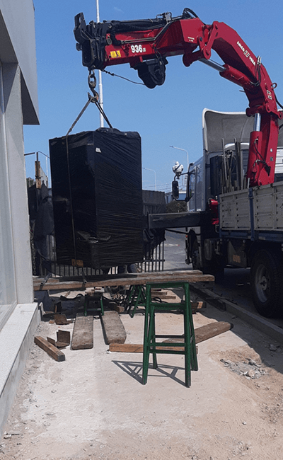 Una grúa roja está levantando una gran caja negra de un camión.