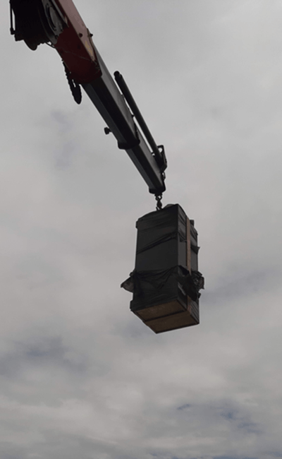 Una grúa levanta una caja grande contra un cielo nublado.