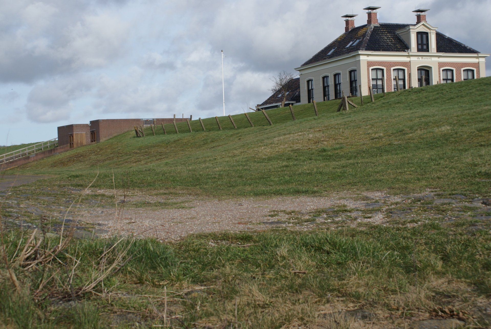 Haus auf einem grasbewachsenen Hügel mit gemauertem Bunker; bedeckter Himmel.