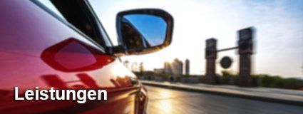 Ein rotes Auto fährt eine Stadtstraße entlang.