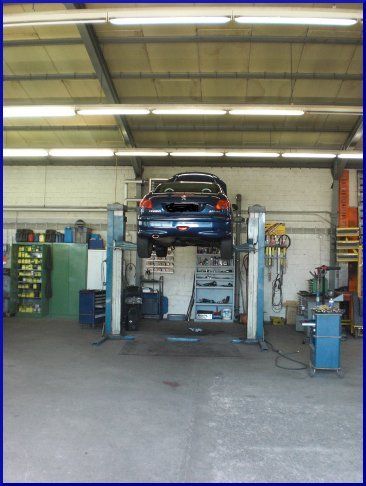 Ein blaues Auto steht auf einer Hebebühne in einer Garage