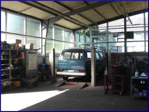 Ein blauer Lieferwagen steht auf einer Hebebühne in einer Garage.