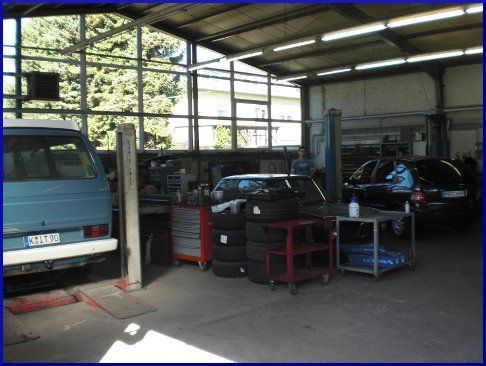 Ein blauer Lieferwagen steht in einer Garage neben einem Stapel Reifen