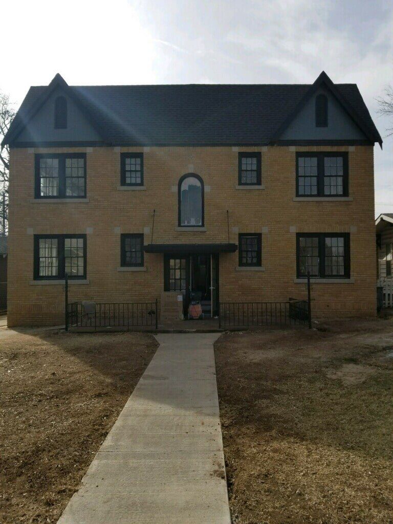 Two-story brick building with a concrete walkway leading to the entrance.