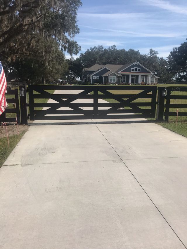 A wooden gate is blocking a driveway to a house.