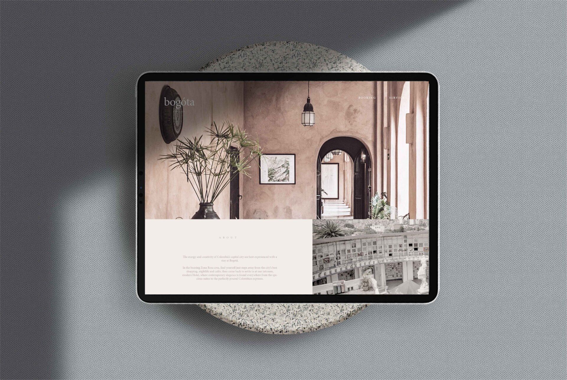 Portátil abierto que muestra una página web de diseño de interiores acogedora sobre una superficie gris texturizada.