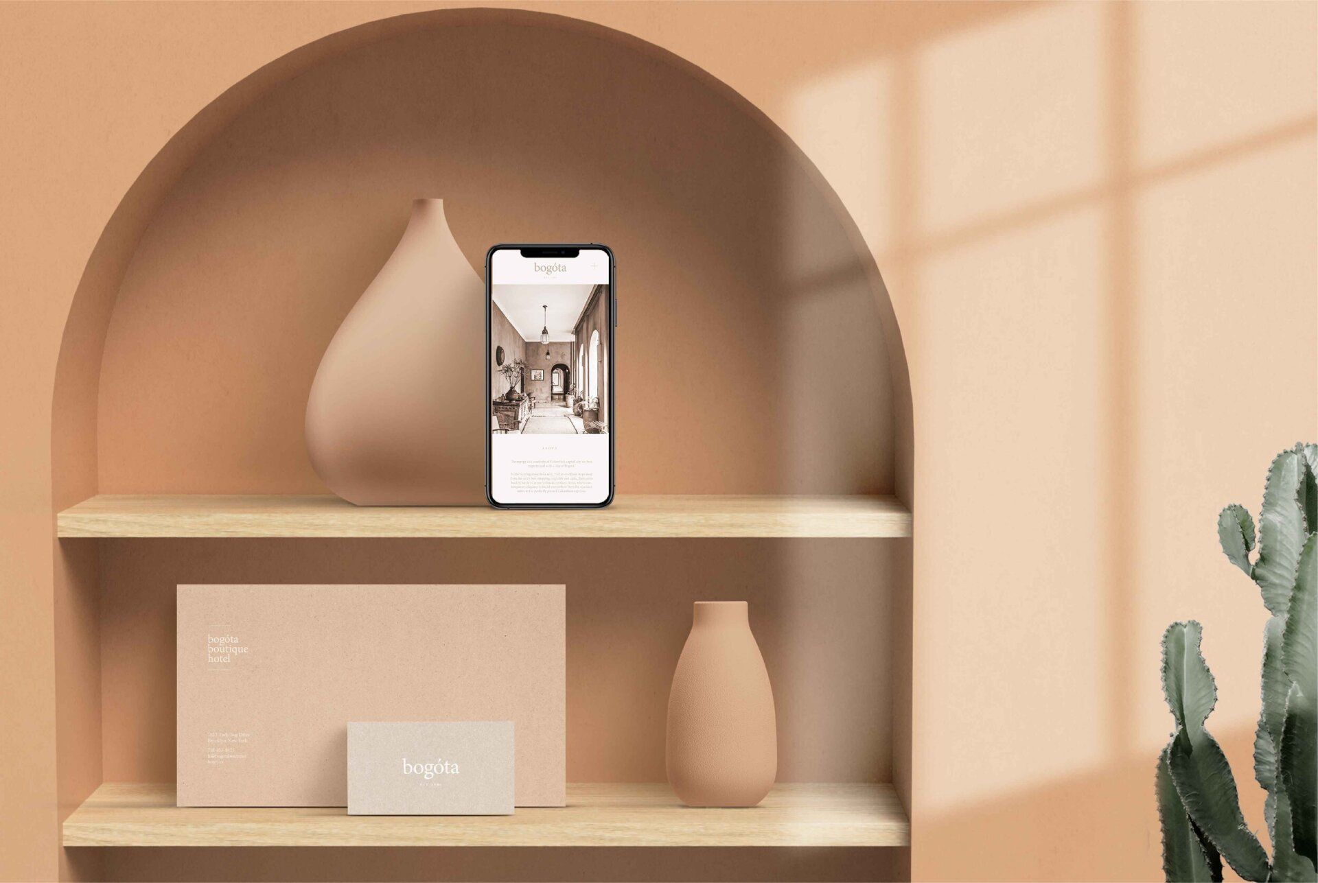 ROM&ROM  Decoración minimalista en una estantería de color beige con un teléfono, un jarrón, cajas y un cactus bajo la cálida luz del sol.