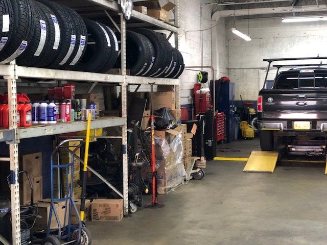 Interior of an auto repair shop with tires on shelves and a truck on a lift.