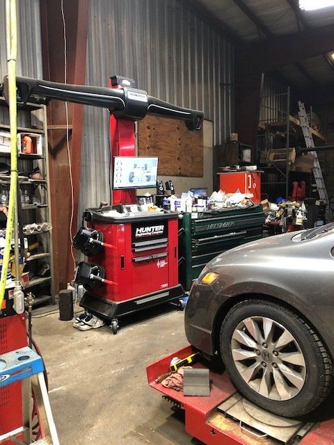 Car being aligned on a lift in a garage with Hunter alignment machine.
