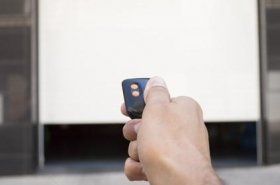 Primo piano di una mano che preme il telecomando per aprire la porta di un garage