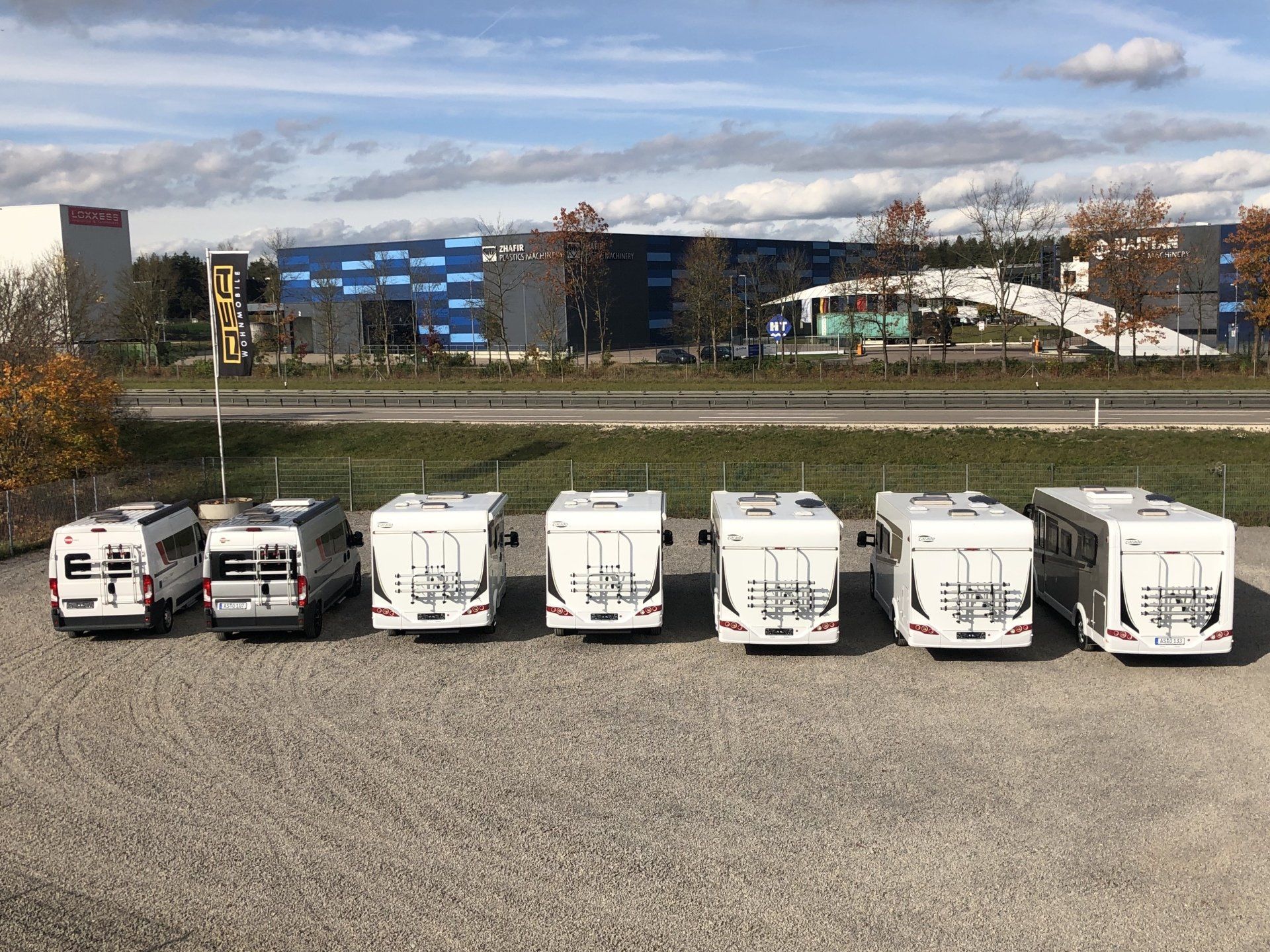 A row of rvs are parked in a parking lot.