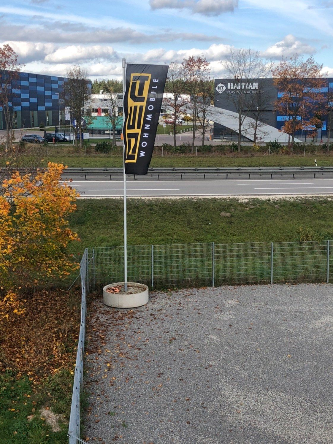A black and yellow flag is hanging from a pole next to a road.