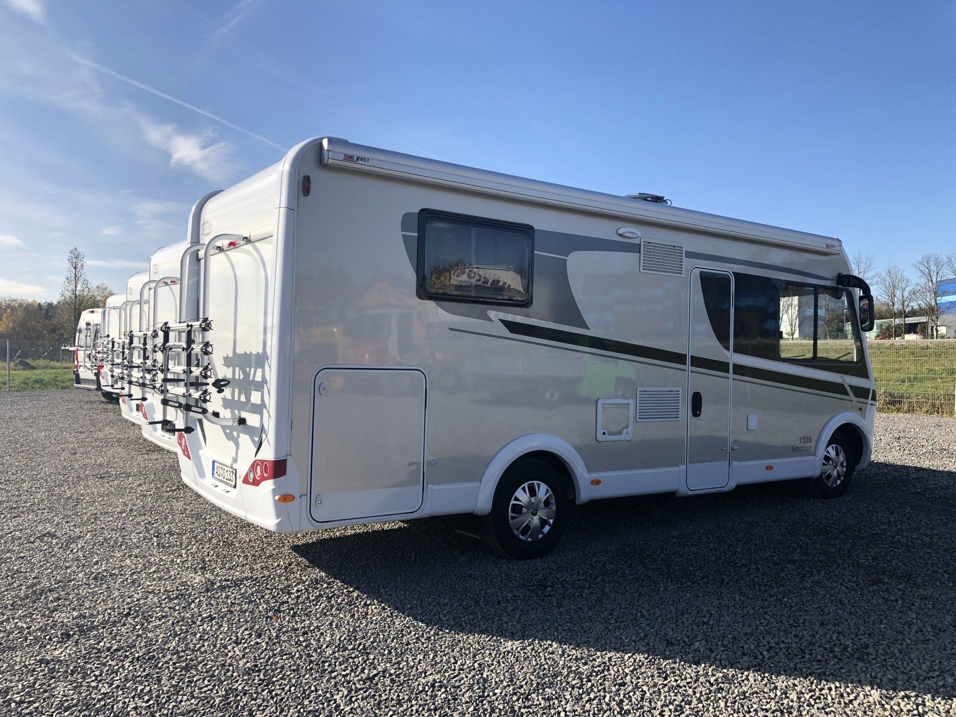 A white rv is parked in a gravel lot.