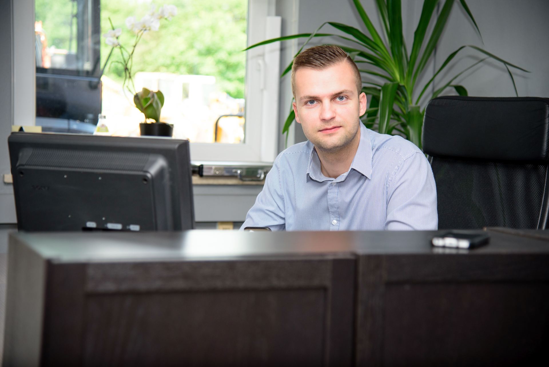 A man is sitting at a desk in front of a computer monitor.