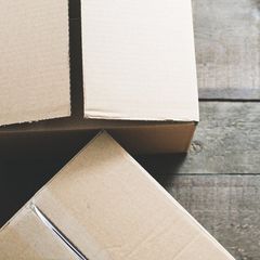 Three cardboard boxes are stacked on top of each other on a wooden floor