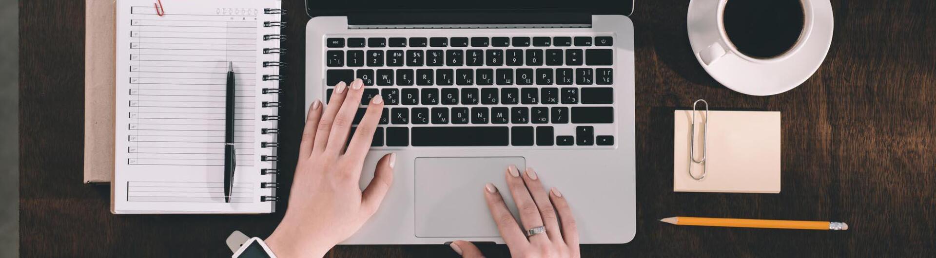 A person is typing on a laptop computer at a desk.