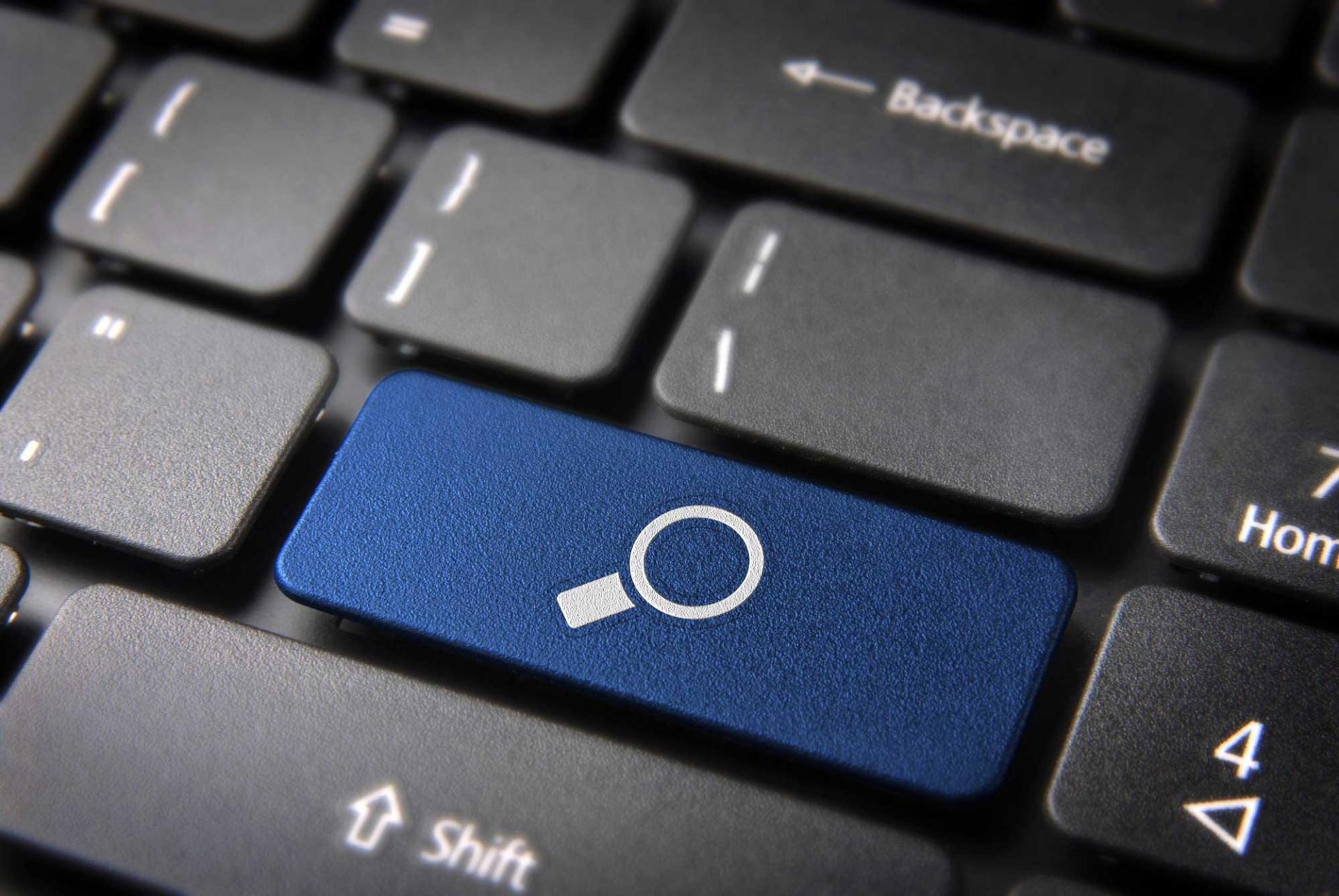 A close up of a keyboard with a blue search key