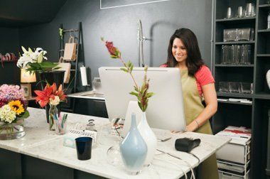 A woman is standing in front of a computer in a flower shop.