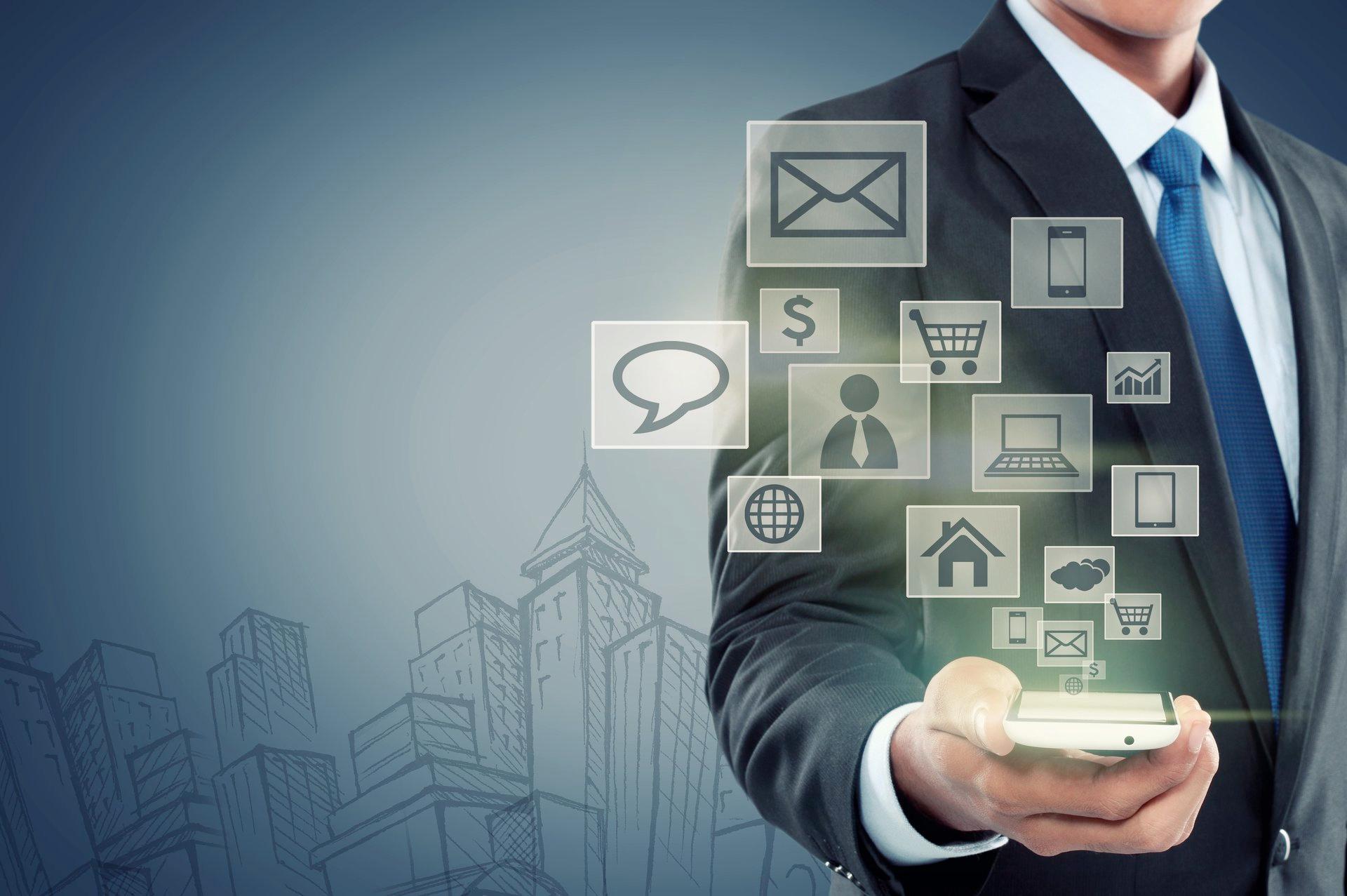 A man in a suit and tie is holding a cell phone with icons coming out of it.