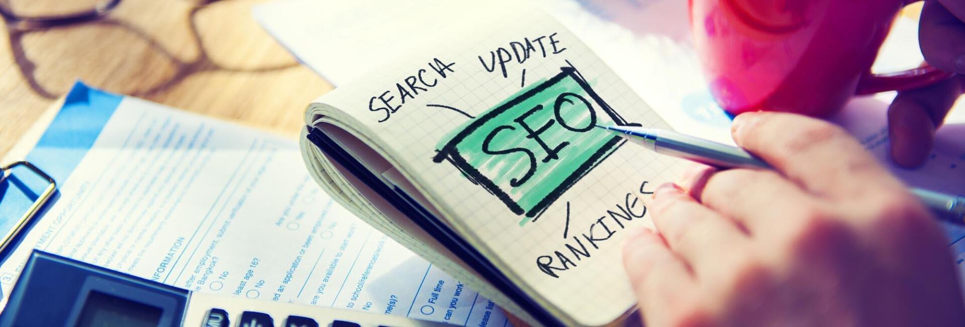 A person is writing on a piece of paper that says seo on it.