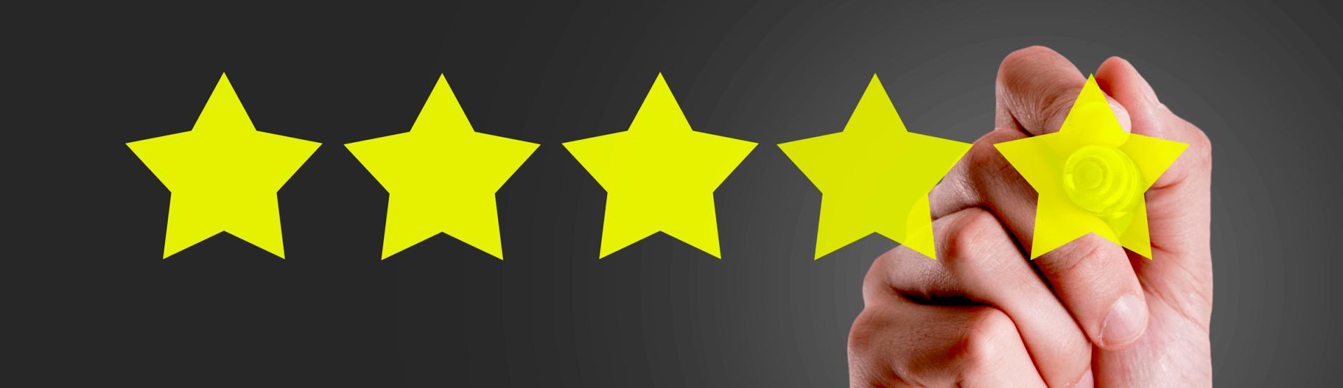 A hand is holding a yellow star in front of a row of yellow stars.