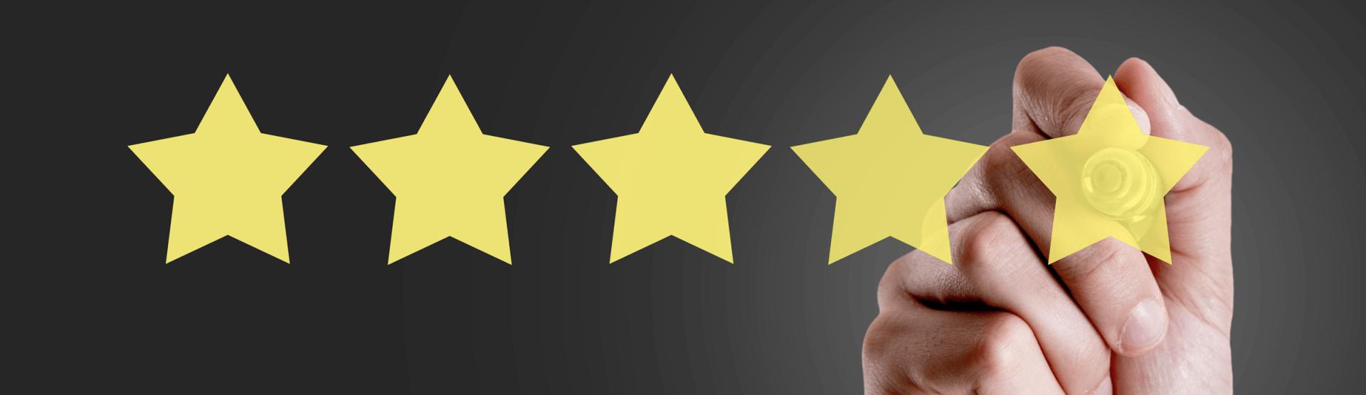 A person is holding a yellow star in front of a row of yellow stars.