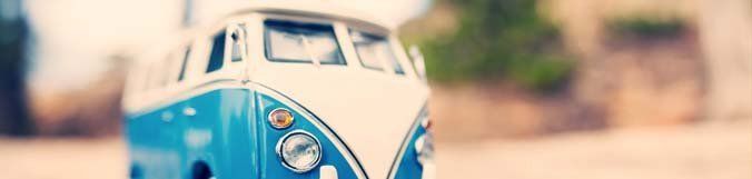 A blue and white toy bus is parked on the side of the road.