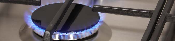 A close up of a gas stove with a blue flame coming out of it.