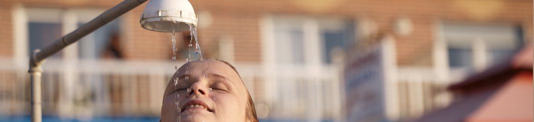 A woman is taking a shower in a swimming pool.