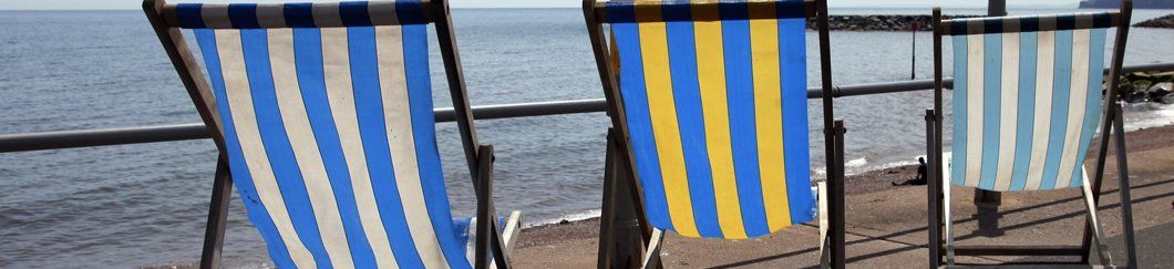 A row of blue and yellow striped beach chairs on a beach.