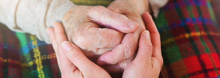A woman is holding an older woman 's hand in a heart shape.