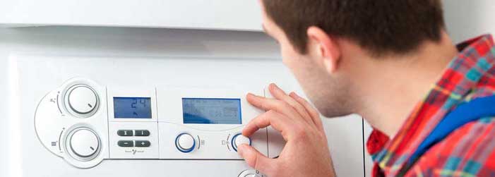 A man is adjusting a thermostat on a wall.
