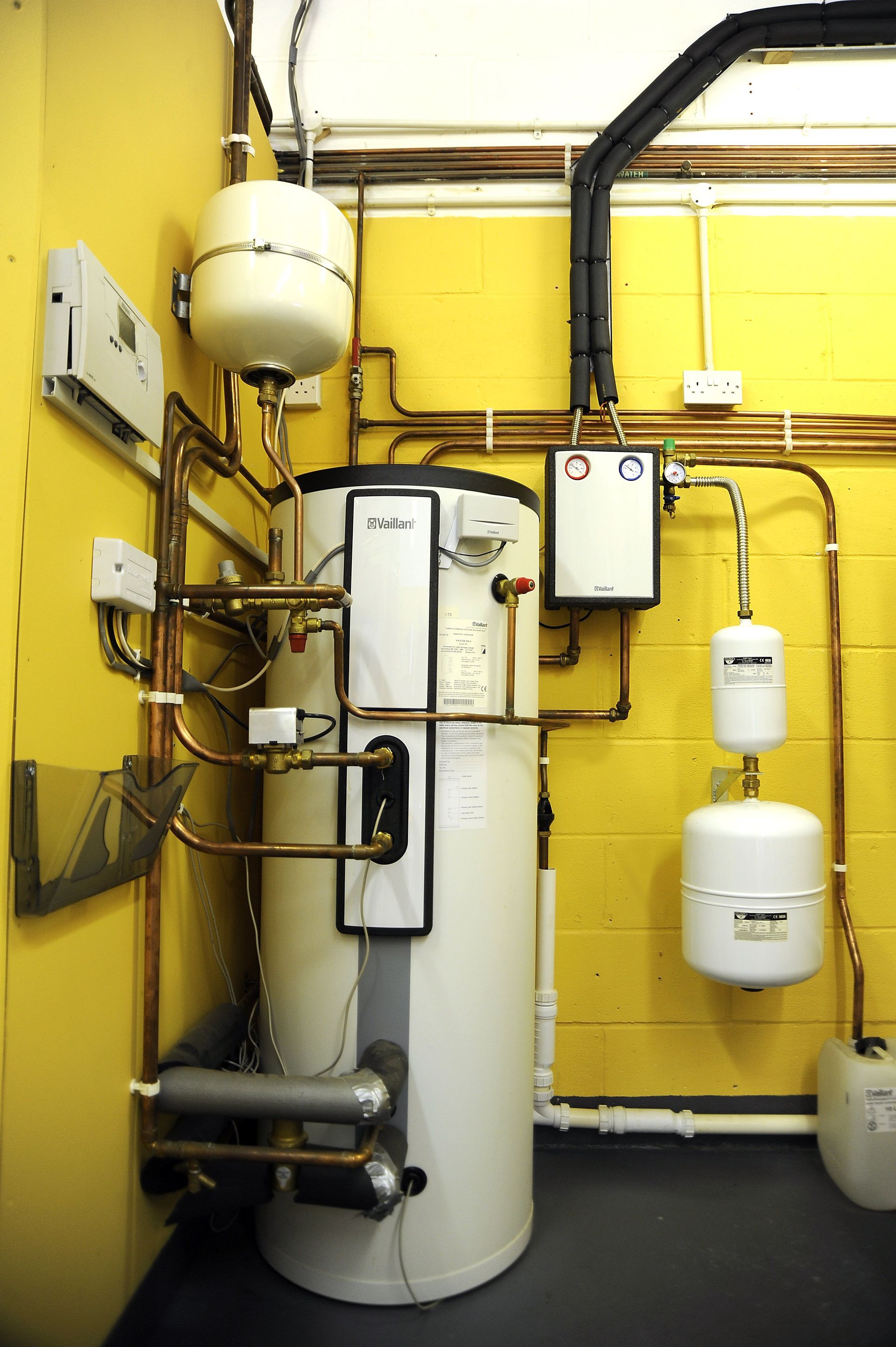 A room with a water heater and a yellow wall