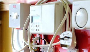 A bunch of wires are hanging on a red wall.