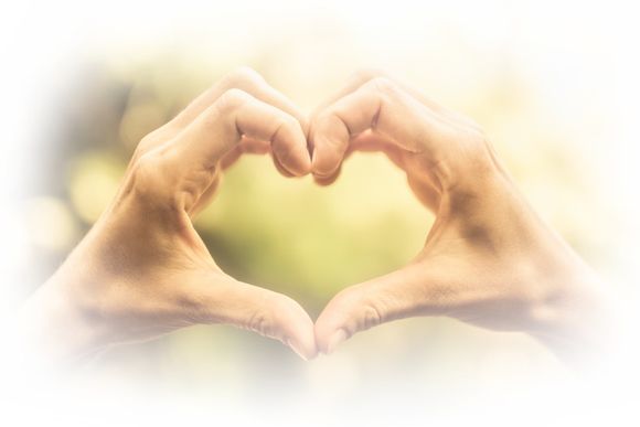 A person is making a heart shape with their hands.