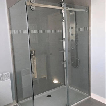 Une salle de bain avec une porte de douche coulissante en verre et une pomme de douche.