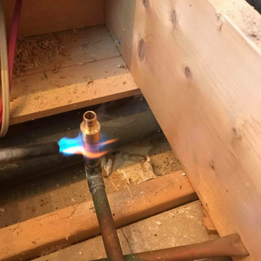 Une flamme sort d'un tuyau dans une pièce en bois.