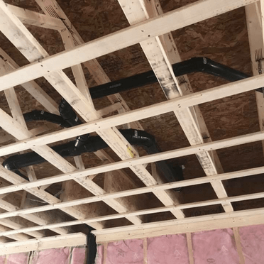 Le plafond d'une maison en construction avec des tuyaux qui en sortent.