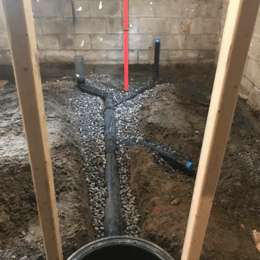 Un tuyau d'évacuation est en cours d'installation dans un sous-sol.