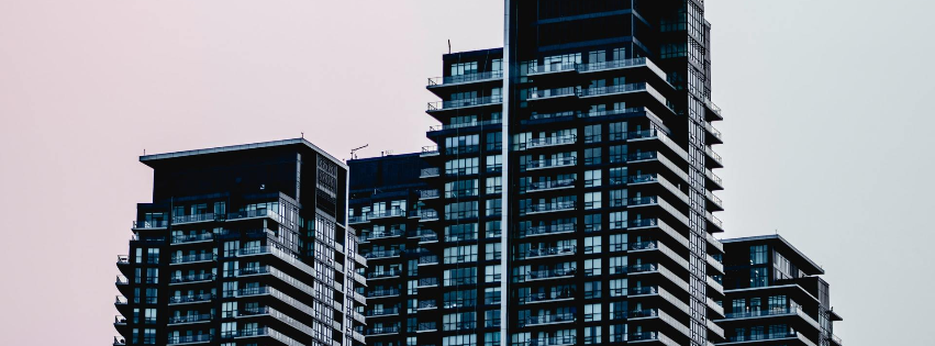 Tall, dark modern apartment high-rise buildings with many balconies against a cloudy sky.