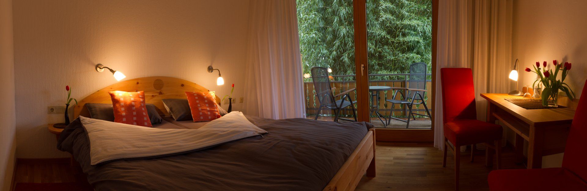 Ein Schlafzimmer mit Bett, Schreibtisch, Stühlen und großem Fenster.
