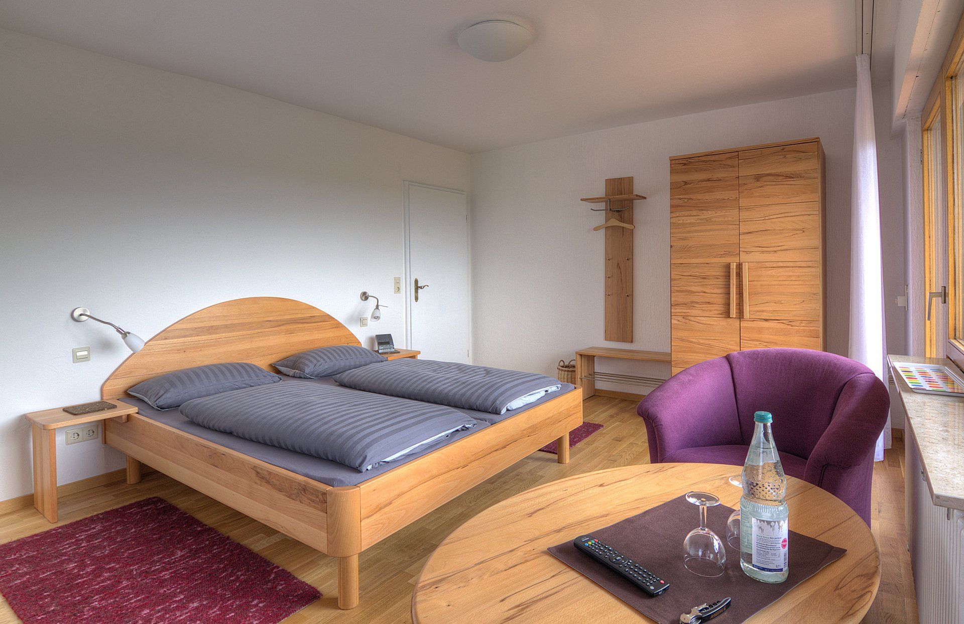 Ein Schlafzimmer mit einem Bett, einem Stuhl, einem Tisch und einer Flasche Wasser auf dem Tisch.