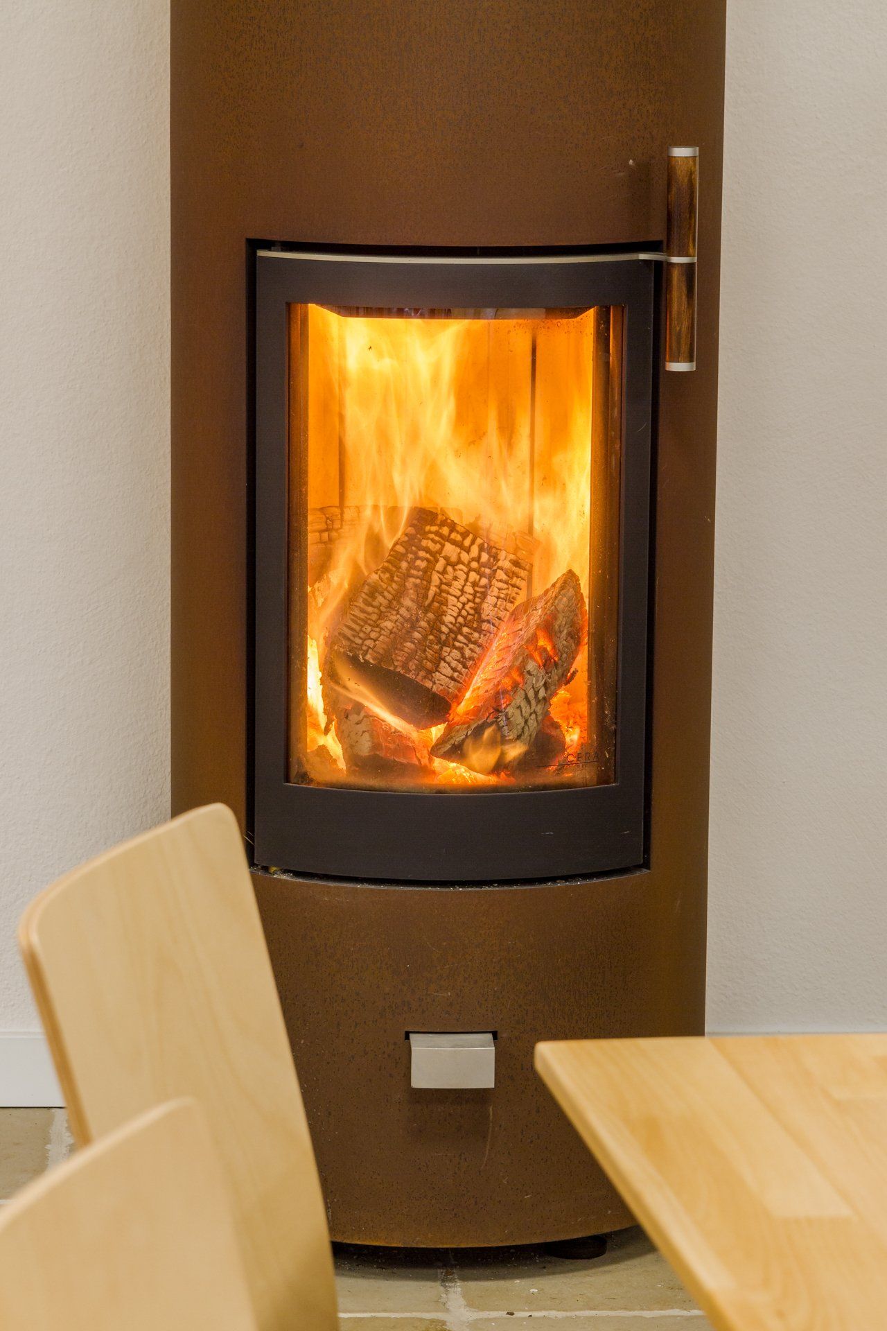 In einem Raum steht ein Holzofen neben einem Holztisch und Stühlen.