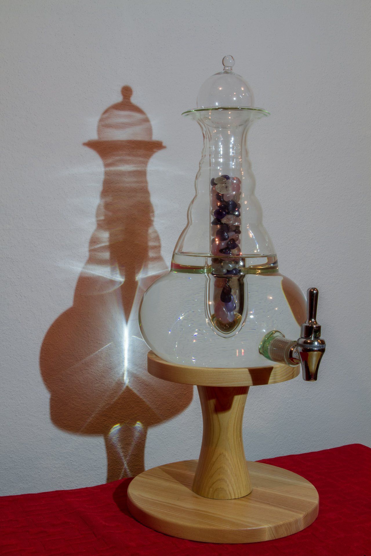 Eine Glasflasche steht auf einem Holzständer auf einem Tisch.