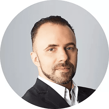 A man with a beard is wearing a suit and white shirt.