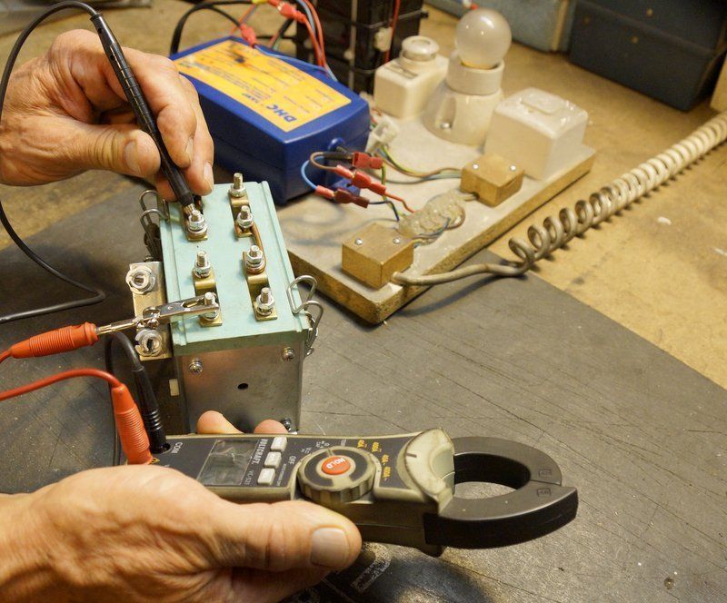 Une personne utilise une pince ampèremétrique pour tester un circuit