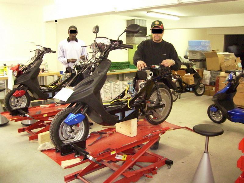 Un homme se tient à côté d'un scooter portant le numéro 17