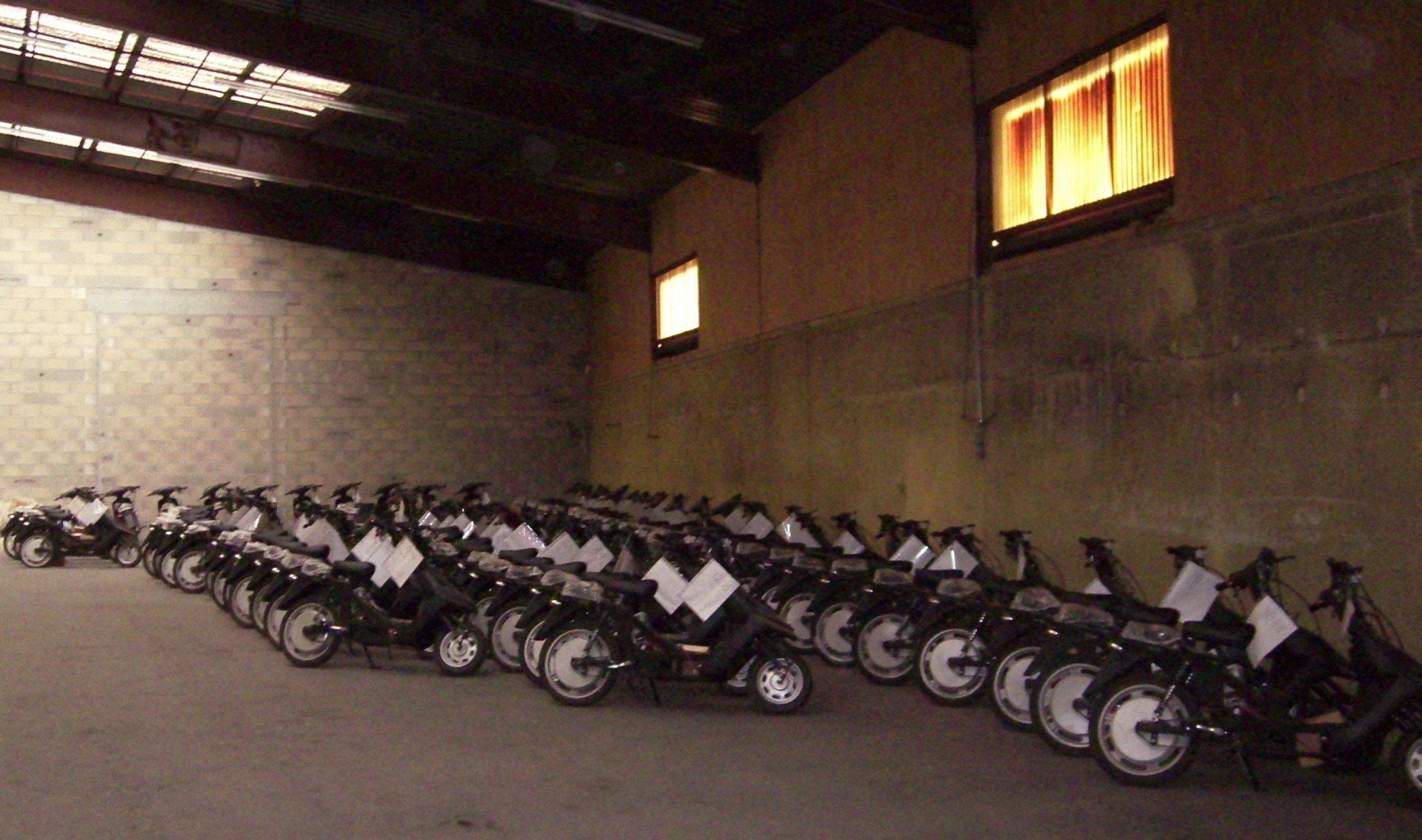 Un tas de scooters sont alignés dans un entrepôt