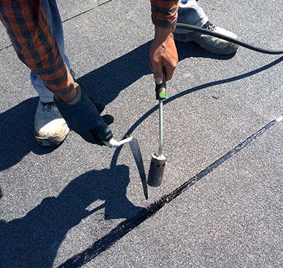 Apartments — Worker Preparing Bitumen Roofing in Muskegon, MI Apartments — Worker Preparing Bitumen Roofing in Muskegon, MI