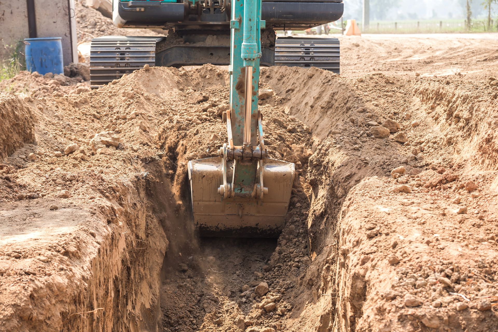 Ein Bagger gräbt im Freien einen Graben in die Erde.